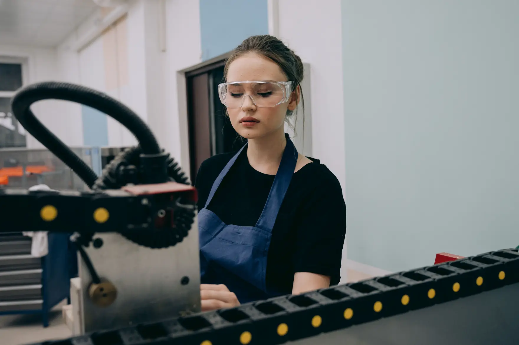 A technician in safety glasses working at a machine in a workshop
